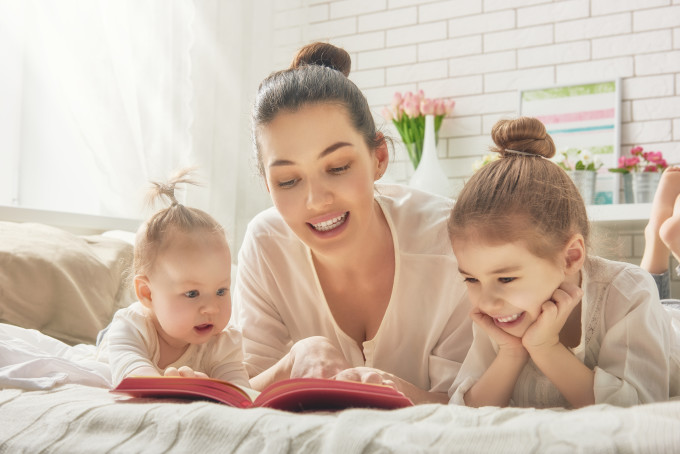 happy loving family. pretty young mother reading a book to her daughters