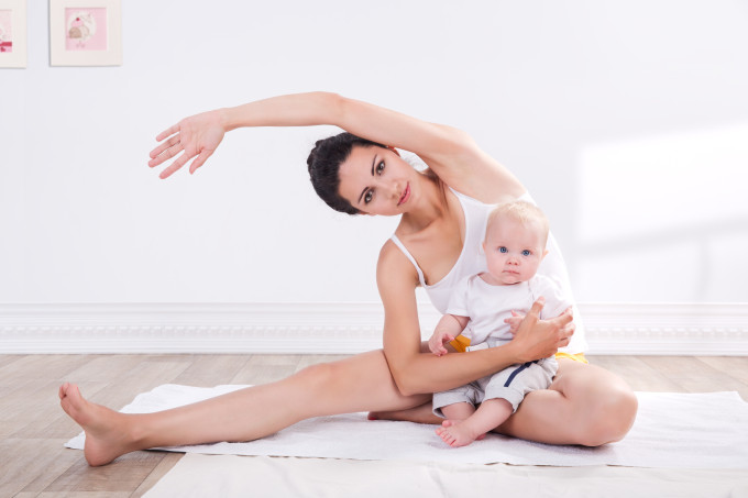 young mother does physical yoga exercises together with her baby