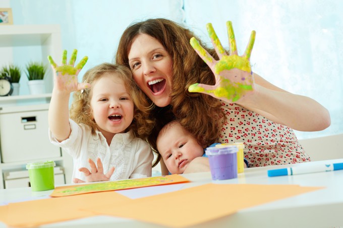 Portrait of a happy family having fun painting with palms and fingers