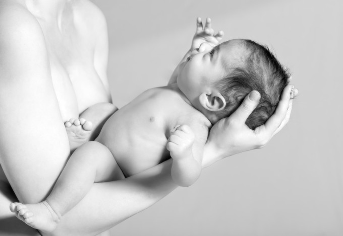Newborn Baby boy on Mother's Arm, at grey background