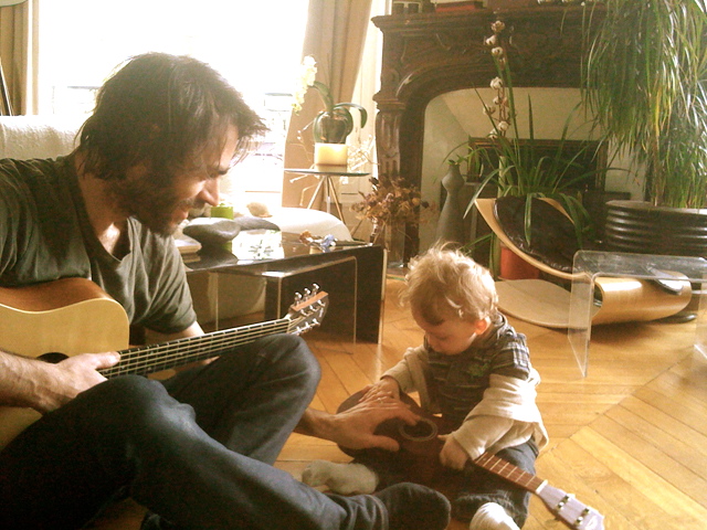 Olivier tocando la guitarra y su hijo 